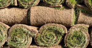 Stack of rolled lawns made of fresh green grass prepared for landscaping work in touristic city